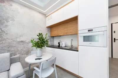 a white kitchen with a table and a refrigerator at Central Apartments by Bed&Bath in Kraków