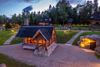 a small house with a fireplace in a yard at Baśniowy Domek Kolędówka z jaskinią SPA - Osada Jaworzyny in Tokarnia