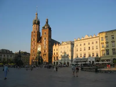 a group of people walking around a city square with a clock tower at Atena - Pantheon Apartments in Kraków