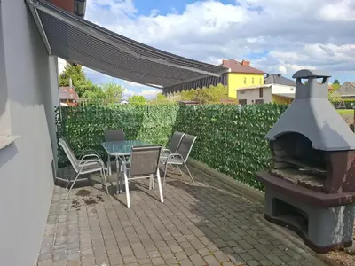 a patio with a table and chairs and a fireplace at Mieszkanie A Łowiczki in Zator
