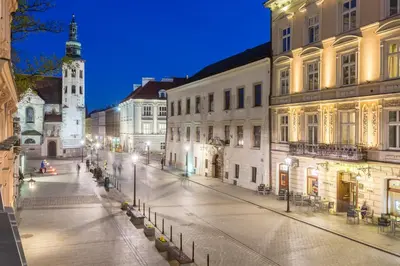 an empty city street at night with a clock tower at Cadena Gallery Apartments Matejko in Kraków