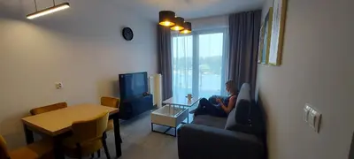 a woman sitting on a couch in a living room at Apartament BARCELONA in Kraków
