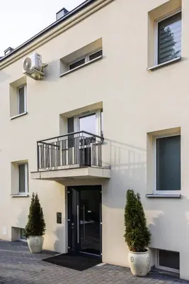 an apartment building with a balcony and two plants at Aleja 69 in Kraków