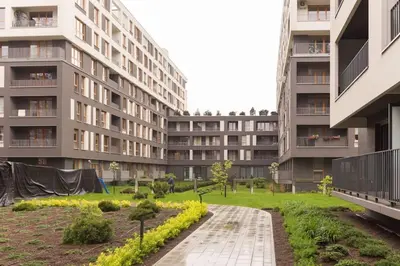 an apartment complex with a garden in front of a building at Zabłocie Cozy Escape in Kraków