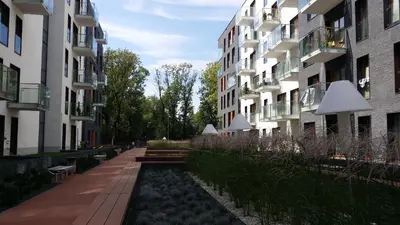 a path between two tall buildings with benches in front at Black Pearl Apartment in Kraków