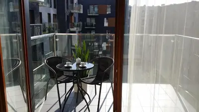 a small table and chairs on a balcony with glass walls at Black Pearl Apartment in Kraków